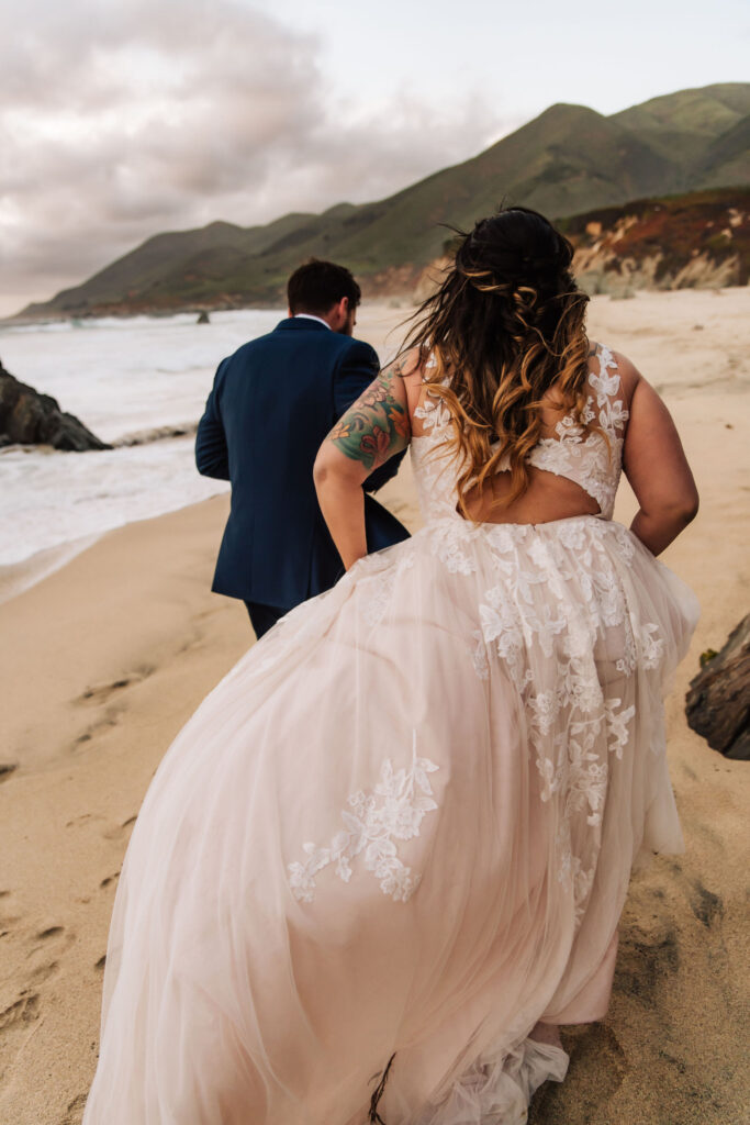 couple running in big sur coastline at their vow renewal elopement 