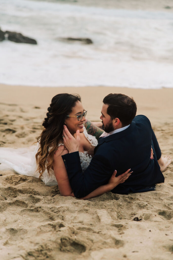 couple lying on the sand looking at each other at their vow renewal elopement 