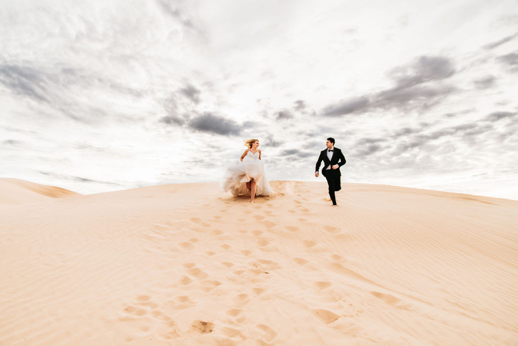 couple that elope in arizona running in the sand dunes